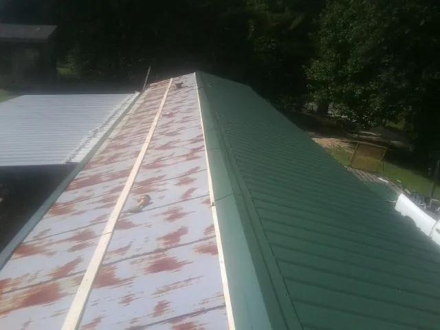 Old rusted panels beside newly installed green metal roofing — Wind Damage Roof Repair by Roofing Brothers in South Dartmouth