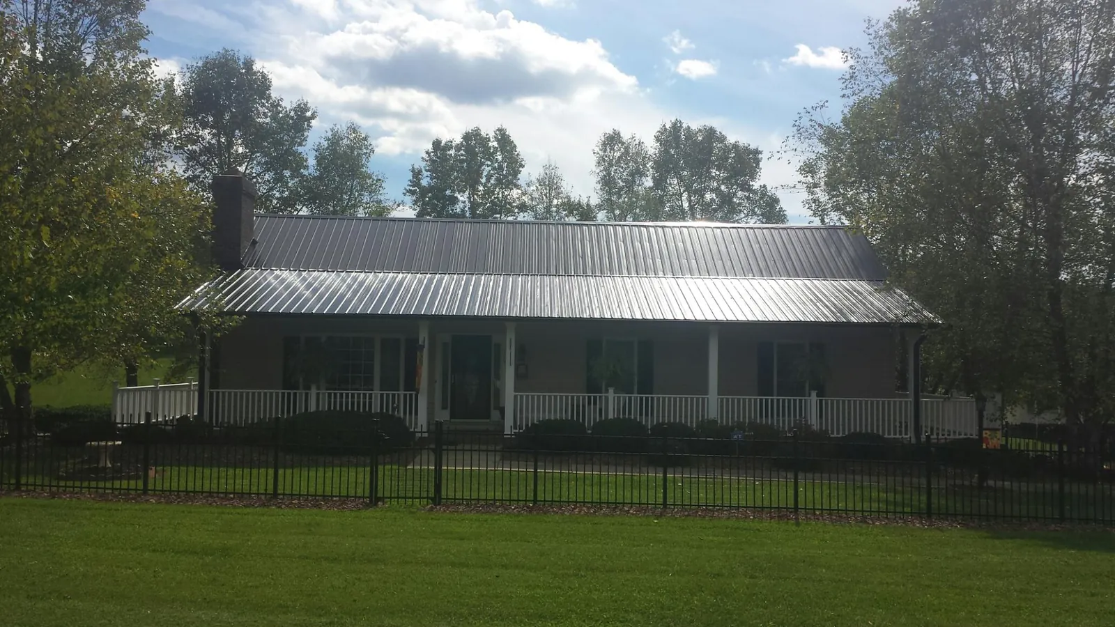 Gray metal roof on a brick ranch with a full width front porch — Gutter Guard Installation work by our crew in South Dartmouth