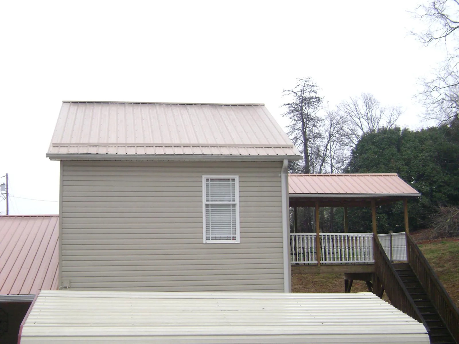 Tan metal roofs on a two story addition and attached porch, from a Roof Replacement job in South Dartmouth