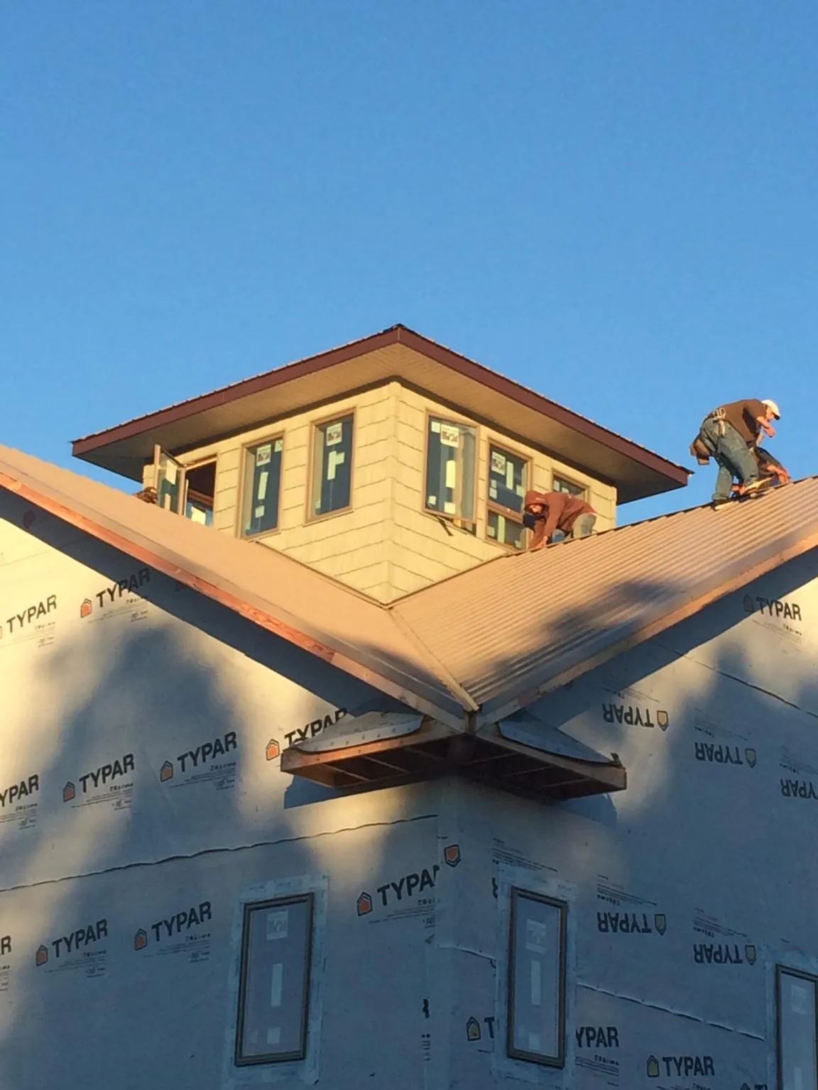 Roofers working around a rooftop cupola on a new metal roof at sunset — Roof Waterproofing in South Dartmouth by Roofing Brothers